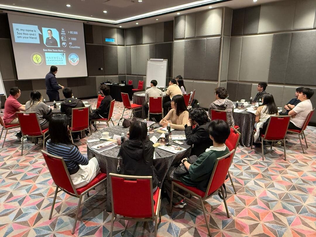 Soo Hoo facilitating a leadership room with participants seated at round tables
